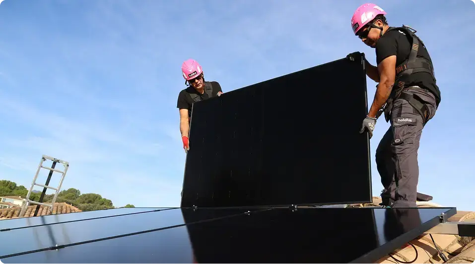 Dos instaladores de Holaluz colocando una placa solar en un tejado